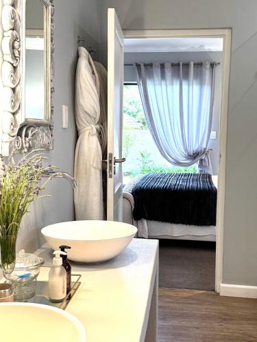 a bathroom with a bowl sink and a bedroom at 10onErika Franschhoek in Franschhoek