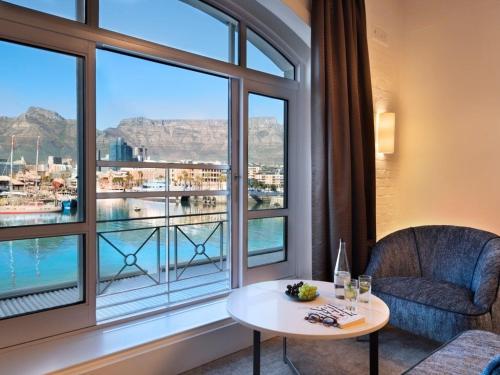 a living room with a table and a large window at Queen Victoria Hotel by NEWMARK in Cape Town