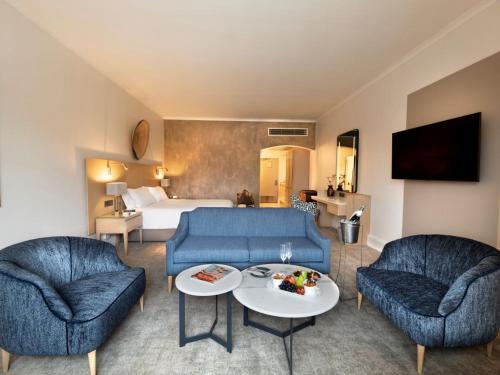 a living room with two blue couches and a bed at Queen Victoria Hotel by NEWMARK in Cape Town