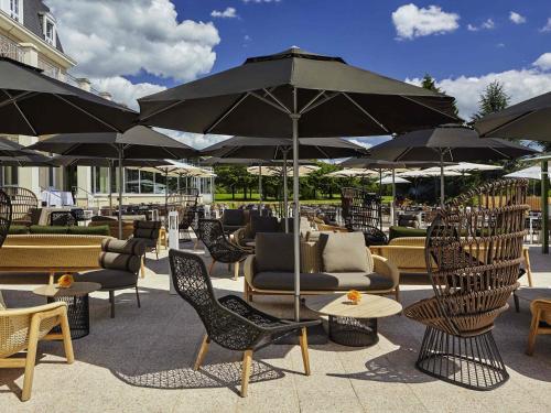 a patio with chairs and tables and umbrellas at Mercure Chantilly Resort & Conventions in Chantilly