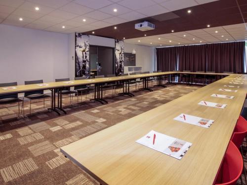 a large conference room with long tables and red chairs at ibis Cahors in Cahors