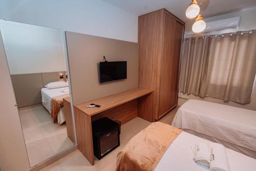 a hotel room with two beds and a television at Sttudio One in Araxá