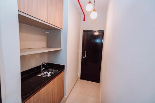 a small kitchen with a sink and a black door at Sttudio One in Araxá