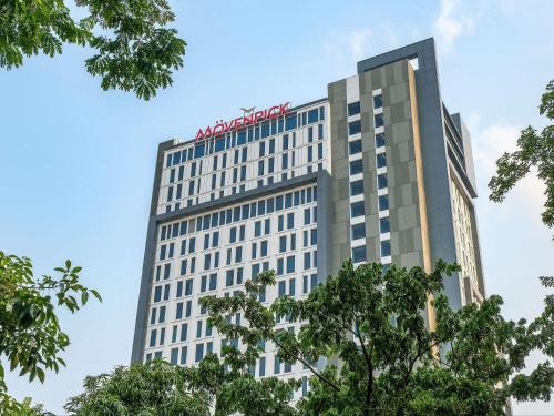 a tall building with a sign on top of it at Movenpick Surabaya City in Surabaya