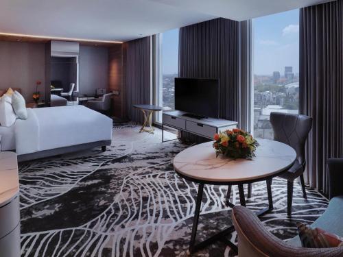 a hotel room with a bed and a table with a television at Movenpick Surabaya City in Surabaya