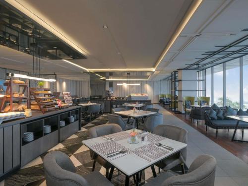 a restaurant with tables and chairs in a room at Movenpick Surabaya City in Surabaya