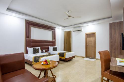 a hotel room with two beds and a table at Hotel Lohmod Suites, Near Indira Gandhi International Airport, New Delhi in New Delhi