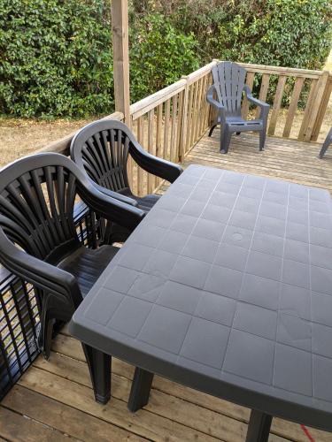 a picnic table and two chairs on a deck at Mobil home Phoenix 6 places in La Boissière-de-Montaigu