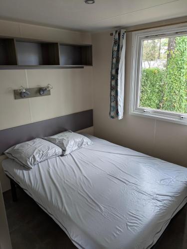 een bed in een slaapkamer met een raam bij Mobil home Phoenix 6 places in La Boissière-de-Montaigu