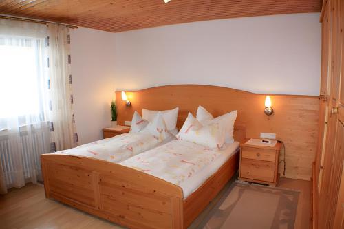 a bedroom with a large wooden bed with white pillows at Schlosshof - Der Urlaubsbauernhof in Elzach