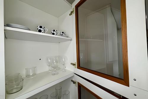 een badkamer met een spiegel en een plank met glazen bij Studio ao lado do Parque da Cidade - Brasília in Brasilia