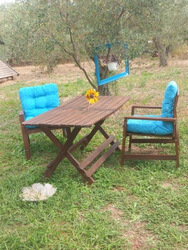 a wooden picnic table and two chairs in the grass at Κτήμα Ανάσες Ζωής- Ευγενία Σγούρα in Epanomi