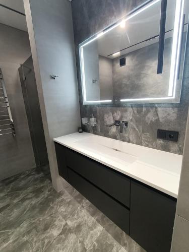 Un baño con lavabo y un espejo grande. en Вишуканий 1к люкс! Megogo, en Khmelʼnytsʼkyy
