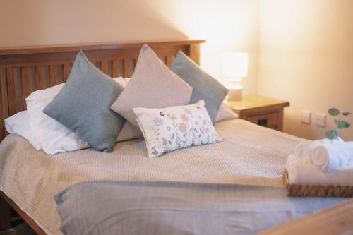 a bed with several pillows on top of it at The Shippon Barn - A delightful haven for families in Wirral