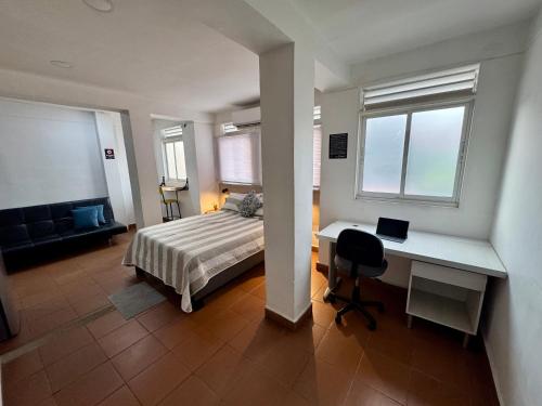 a bedroom with a bed and a desk with a laptop at OUR HOME SAN ANTONIO in Cali