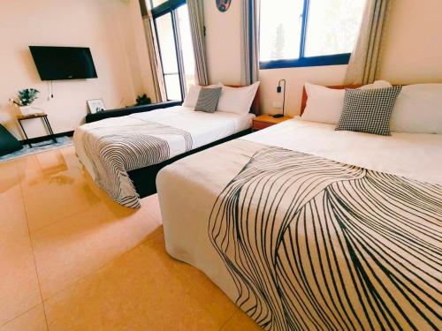 a room with two beds and a television in it at 小憩人輕旅 in Jinning