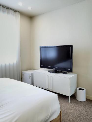 a bedroom with a flat screen tv on a white cabinet at jeonju hotel book and type in Jeonju