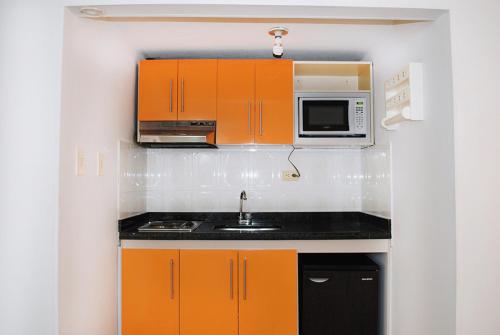 a kitchen with orange cabinets and a microwave at 100 Wonderful House in Bogotá