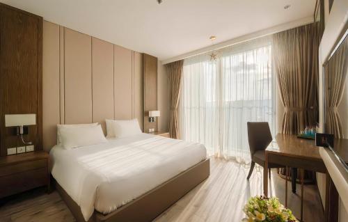 a bedroom with a bed and a desk and a window at VELA OCEAN LUXURY SUITES Nha Trang Centre in Nha Trang