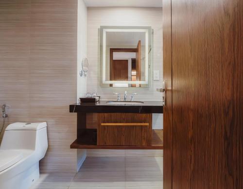 a bathroom with a sink and a toilet and a mirror at VELA OCEAN LUXURY SUITES Nha Trang Centre in Nha Trang