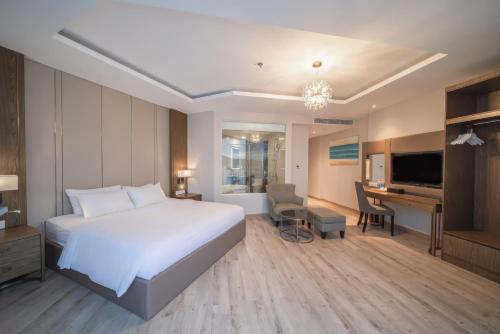 a bedroom with a large white bed and a desk at VELA OCEAN LUXURY SUITES Nha Trang Centre in Nha Trang