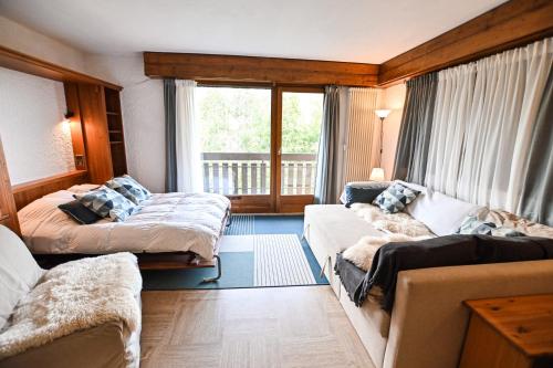 une chambre avec deux lits et un canapé et une fenêtre dans l'établissement Charmant 50m avec BALCON à Megève !, à Megève