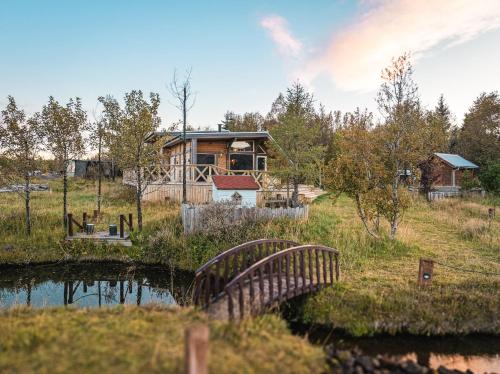 a house on a hill next to a body of water at Riverside Cabin - Hot Tub, Fishing and Relaxing Escape in Laugarvatn