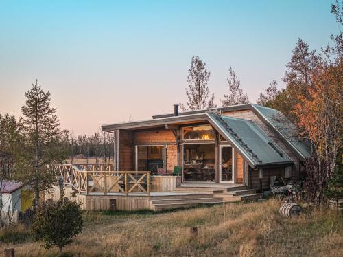 a house on a hill with a wrap around porch at Riverside Cabin - Hot Tub, Fishing and Relaxing Escape in Laugarvatn