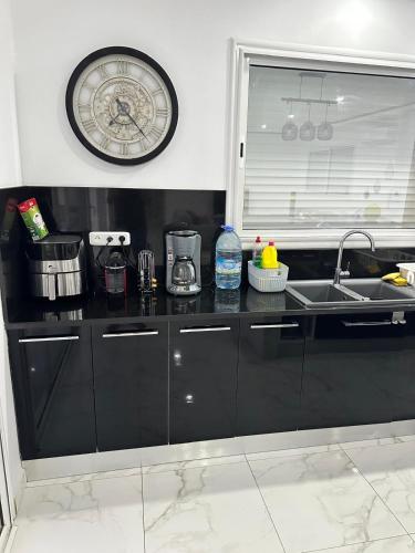 a kitchen with a sink and a clock on the wall at Beautiful villa for a stay in Djerba in Al Ḩaddādah