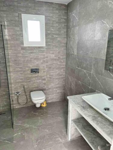 a bathroom with a toilet and a sink and a shower at Beautiful villa for a stay in Djerba in Al Ḩaddādah