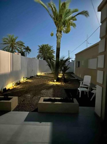 a courtyard with a palm tree and a building at Beautiful villa for a stay in Djerba in Al Ḩaddādah