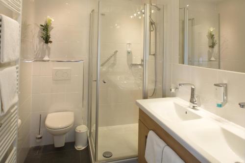 a bathroom with a shower and a toilet and a sink at Kur- und Wellnesshotel Förch in Bad Wörishofen