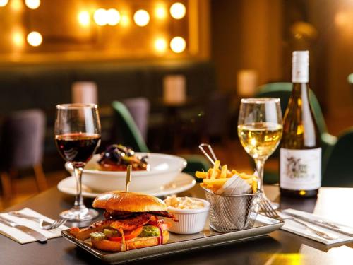 a table topped with a sandwich and glasses of wine at Mercure Birmingham West Hotel in West Bromwich
