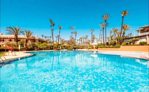 a large swimming pool in a resort with palm trees at Palmeraie village , lieu exceptionnel avec jardin et piscine in Marrakech