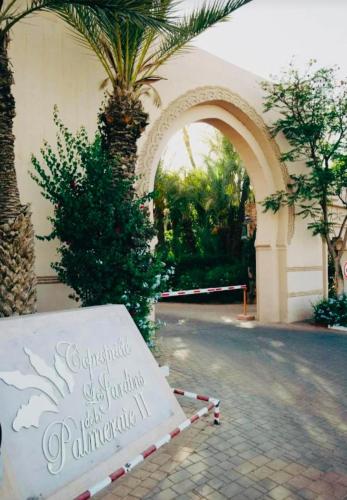 a sign in front of a building with a palm tree at Palmeraie village , lieu exceptionnel avec jardin et piscine in Marrakech