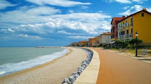 a beach with a row of buildings and the ocean at Bright villa in Caorle with private garden in Caorle
