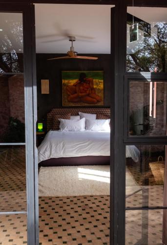 a bedroom with a bed with a painting on the wall at CASA MISASHA nature, calme, bio et vos repas préparés par notre cuisinière in Essaouira