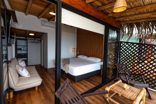 a bedroom with a bed and a couch and a chair at Hoja de Palma Bungalows in Canoas De Punta Sal