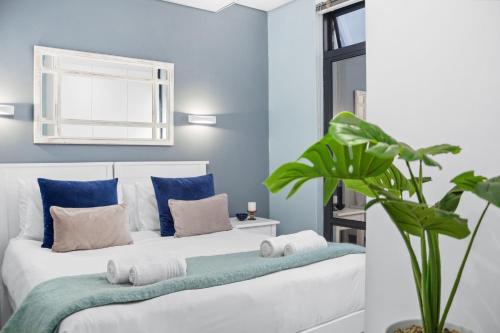 Un dormitorio con dos camas con paredes azules y una planta. en Eden On The Bay 67A by Host Agents, en Big Bay