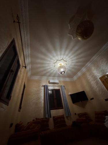Una habitación con una lámpara de araña en el techo y una ventana. en Sinbad Hostel, en Merzouga