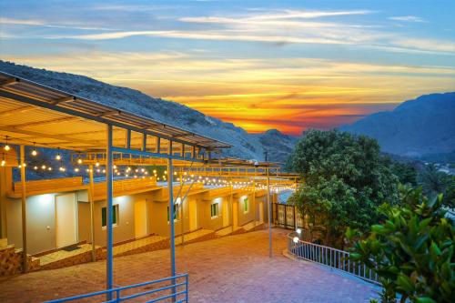 a building with a view of the mountains at sunset at The Sunshine Farm by Al Dana Paradise Luxury 6BR Secluded Nature Mountains in Khor Fakkan
