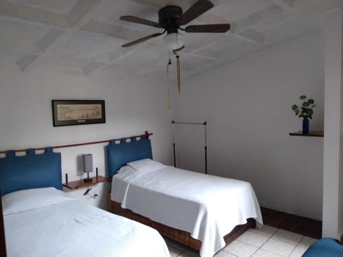 a bedroom with two beds and a ceiling fan at La Super Casa en Palmira in Cuernavaca