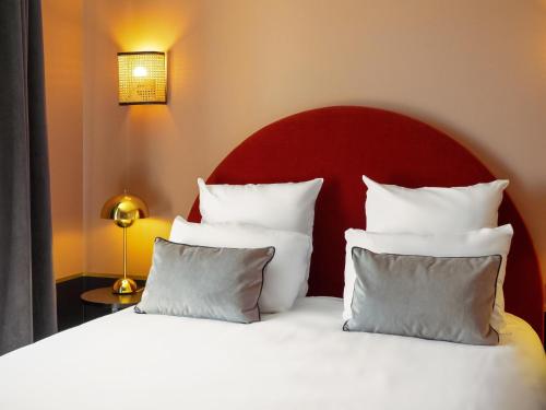 a bed with a red headboard and white pillows at Hotel Mercure Roscoff Bord De Mer in Roscoff