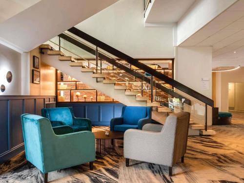 a living room with two chairs and a staircase at Mercure Bedford Centre Hotel in Bedford