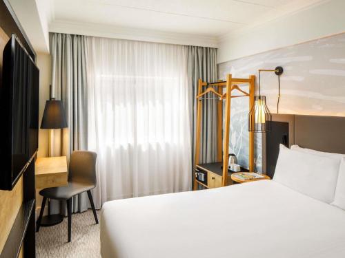 a hotel room with a white bed and a desk at Mercure Bedford Centre Hotel in Bedford