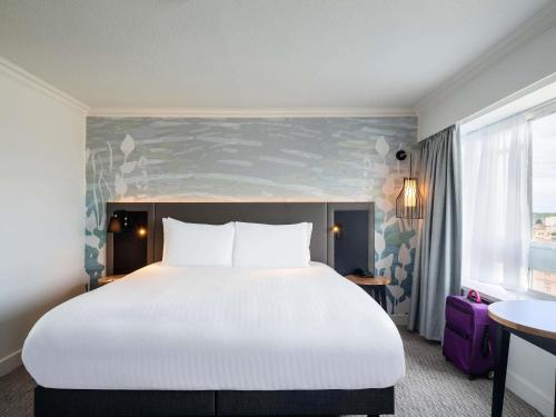 a hotel room with a large bed and a window at Mercure Bedford Centre Hotel in Bedford
