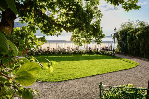 a grassy area with a large building in the background at Hotel Vitznauerhof - Lifestyle Hideaway at Lake Lucerne in Vitznau