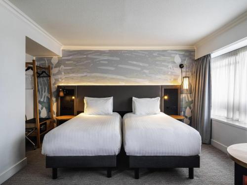 two beds in a hotel room with white pillows at Mercure Bedford Centre Hotel in Bedford