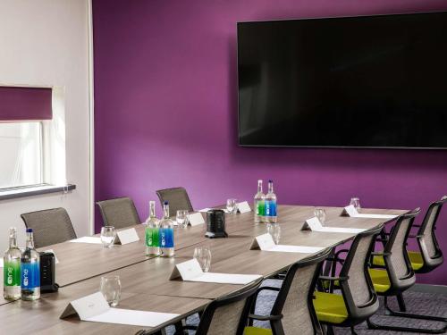 a conference room with a long table with chairs and a flat screen tv at Mercure Bedford Centre Hotel in Bedford