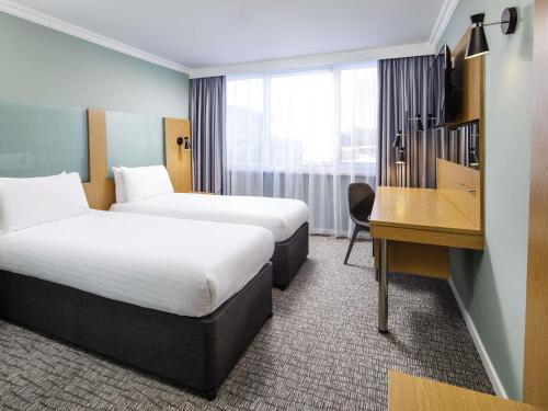 a hotel room with two beds and a desk at The Harlow Hotel By AccorHotels in Harlow